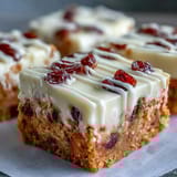 Thick, creamy orange cream cheese frosting is spread over the warm bars, creating a glossy, festive finish for the dessert bars.