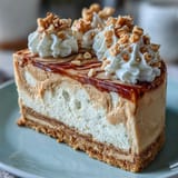 Smooth peanut butter cheesecake topped with fluffy whipped cream and chopped peanuts on a Nutter Butter crust. 