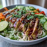 Drizzled with a sweet-savory sauce and garnished with cilantro, sesame seeds, and lime wedges for a bright finish.