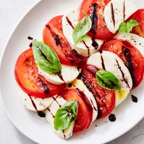 Beautiful Caprese salad, showcasing juicy tomatoes and creamy mozzarella drizzled with balsamic glaze.