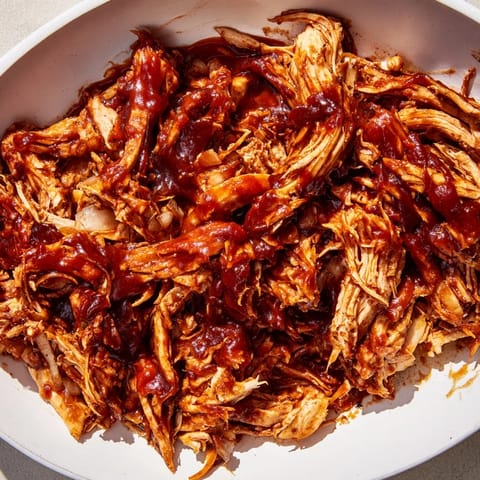 Tender, juicy BBQ pulled chicken, perfect for sandwiches, piled high and glistening with sauce.