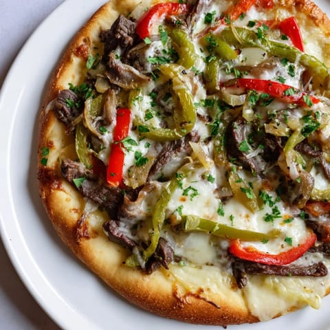 Melted cheese bubbles over a Philly Cheesesteak Pizza, a satisfyingly savory American classic.