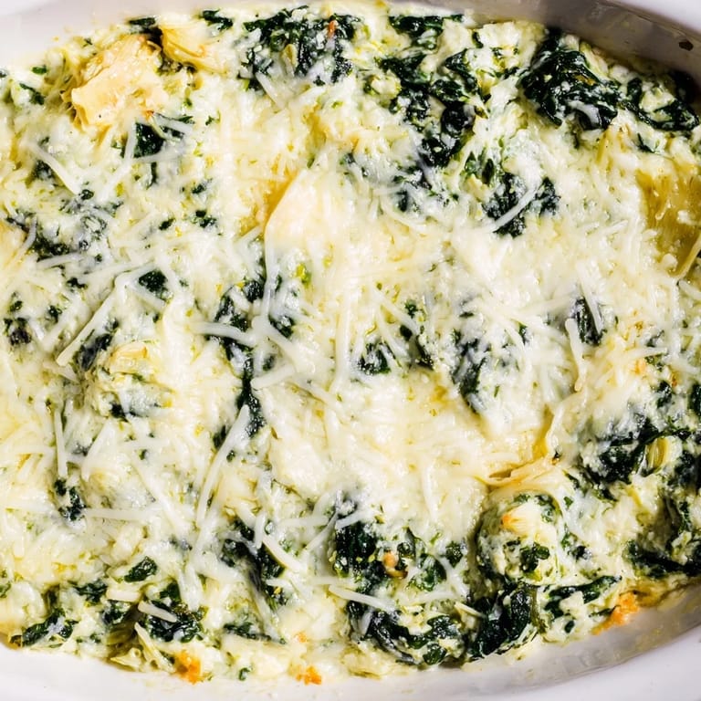 A close-up shot of rich Spinach Artichoke Dip, perfect for a party, with cheesy, bubbly goodness.