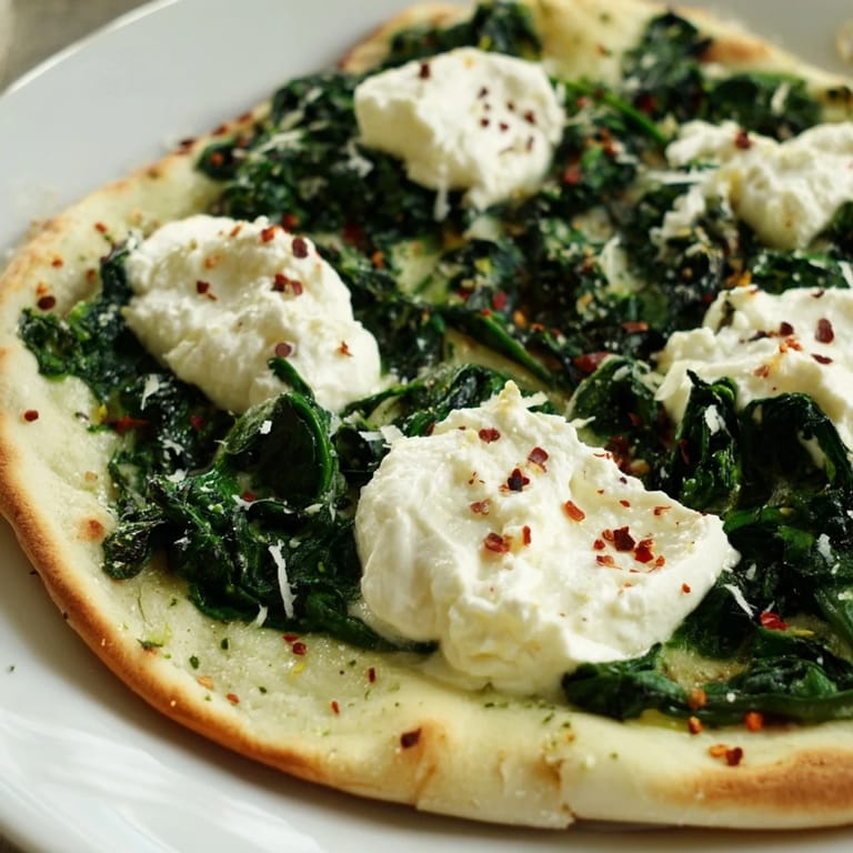 Overhead view of a whole Spinach Ricotta Pizza on a wooden board, ready to serve with a side salad and Pinot Grigio.