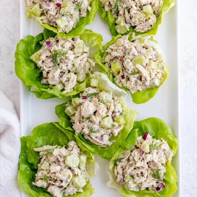 Chilled dill pickle chicken salad in lettuce cups, topped with extra dill and finely chopped pickles.
