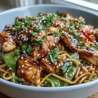 Tender chicken and crisp bell peppers in a glossy sesame sauce over noodles in a Sesame Chicken Noodle Bowl. 